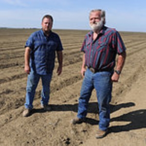Jim Diedrich (L) and his son Todd stand on some of their farmland which will not be planted this season due to lack of water, in Firebaugh, California.