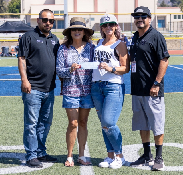 On Saturday, September 21, the Fillmore Women’s Service Club donated a $500 check to the Fillmore Raiders Youth Football & Cheer Organization. Pictured are the members from both organizations on the 50-yard line as the FWSC presents them with the check. Photo credit Crystal Gurrola.
