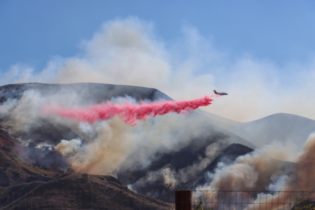 A fixed-wing plane drops red flame retardant on the Mountain Fire. Photo credit Angel Esquivel.