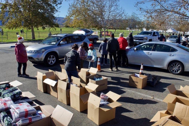 On Saturday, December 11th from 9am to noon at Fillmore’s Two Rivers Park, cars lined up for the Fillmore Community Holiday Giveaway. Families received age-appropriate toys, reading books and socks pre-packaged for pick-up. They also received blankets and a holiday bag of groceries if needed. Above and below, cars driving by to pick up their goodies, and volunteers helping package and hand them out. Photos courtesy Angel Esquivel-AE News. 