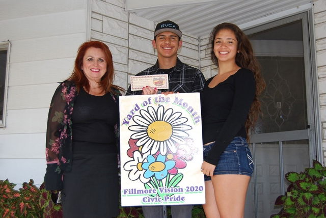 Theresa Robledo, assisting with the presentation of Fillmore Vision 2020 Civic Pride’s Yard of the Month for June awarded to Mr. and Mrs. Gutierrez. However Mr. and Mrs. Gutierrez were a little camera shy so their children Enrique and Mariela accepted the award on their behalf. Their yard has lushes greens, beautiful manicured trees, and vibrant colored roses. Please feel free to drive by their yard located at El Dorado Space #26. A big Thank you to Otto And Sons!