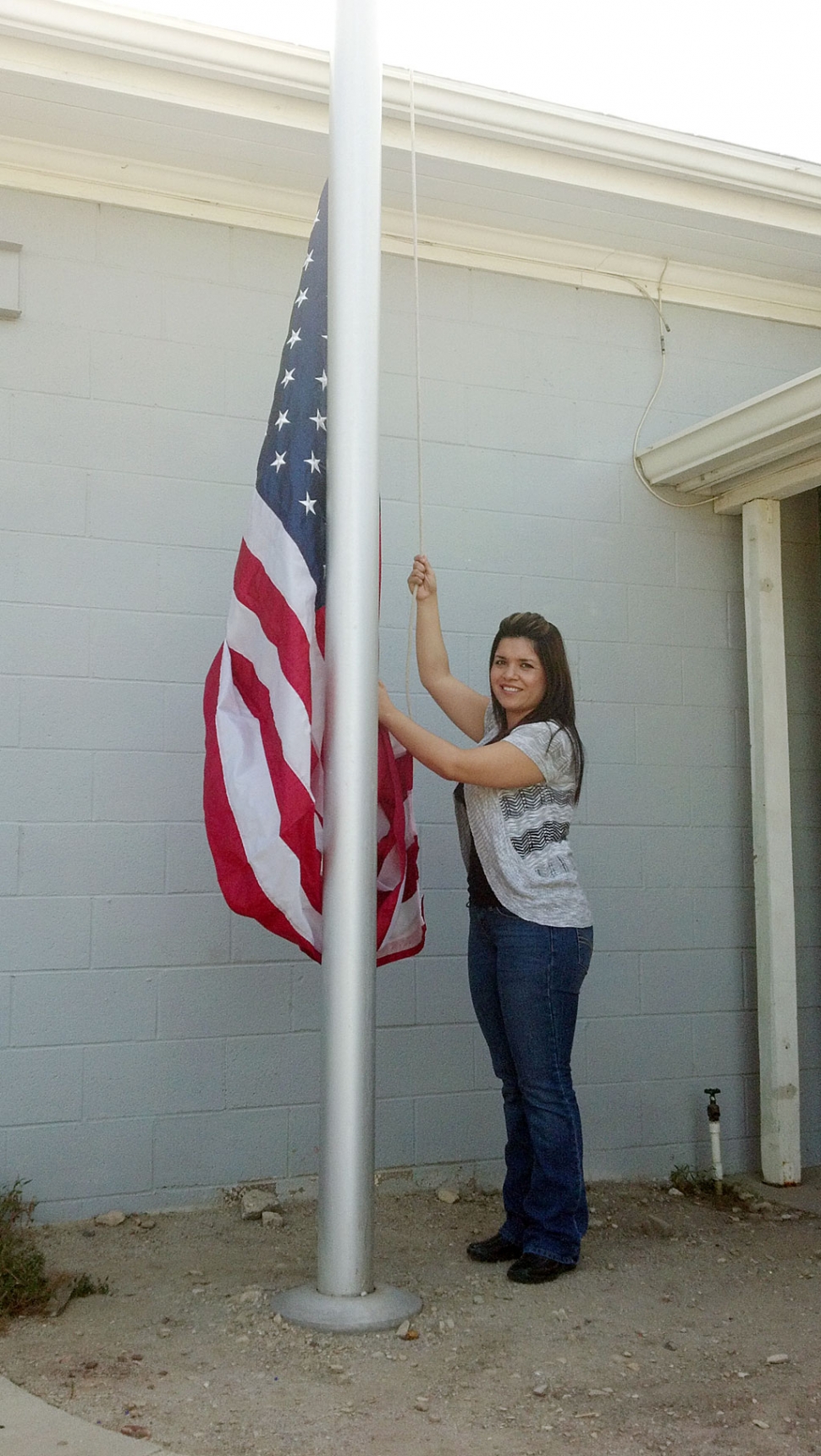 Sylvia Meza, Administrative Assistant for Solid Terrain Modeling proudly raises the American Flag.